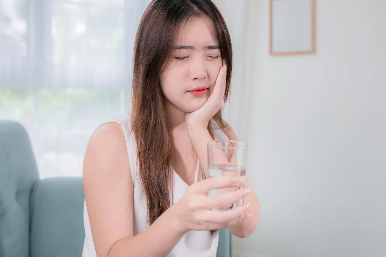 A glass of water beside a dental mirror, illustrating the connection between hydration and the health of the teeth, gums, and breath.